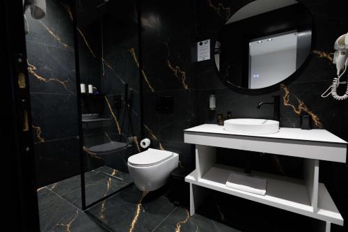 a bathroom with a toilet and a sink and a mirror at Destiny Hotel & SPA in Tirana