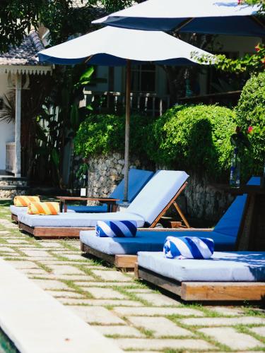 a row of lounge chairs with an umbrella at Villa Olala Penida in Toyapakeh