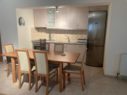 een keuken met een tafel, stoelen en een koelkast bij Joanna's House in Néa Péramos