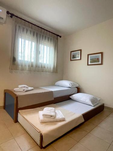 two beds in a room with a window at Joanna's House in Nea Peramos