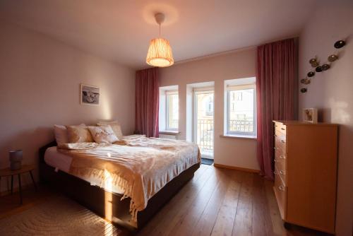 a bedroom with a bed and a dresser and windows at Angelica Apartment in Vilnius