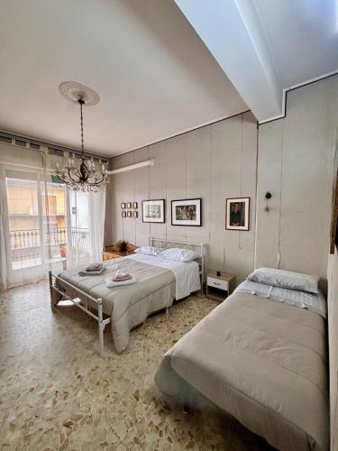 a bedroom with two beds and a chandelier at Appartamento turistico Giarre Offre Camera in condivisione Euro 300 al mese in Giarre