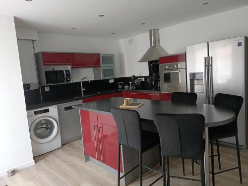 une cuisine avec des placards rouges et une table avec des chaises dans l'établissement Appartement avec Balnéo, à Montreux-Château