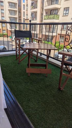 a picnic table and a chair on a balcony at Sulwe homes 5 MINUTES FROM JOMO KENYATTA INTERNATIONAL AIRPORT in Nairobi