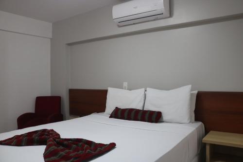 a white bed with two pillows on top of it at Hotel Nacional Inn Curitiba Estação Shopping in Curitiba