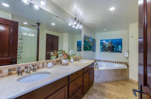 a bathroom with two sinks and a tub and a large mirror at Waipouli Beach Resort E301 in Kapaa