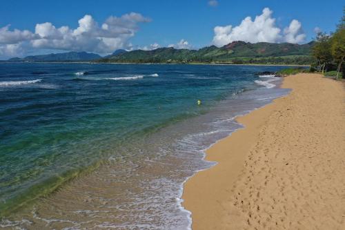 a sandy beach with the ocean and mountains in the background at Islander on the Beach 246 in Wailua