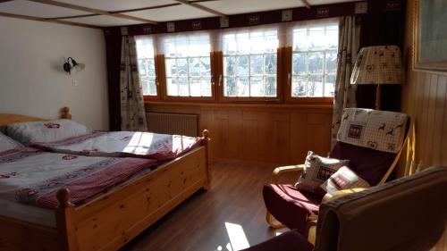 a bedroom with a bed and a chair and windows at Gästehaus Krone in Schönengrund