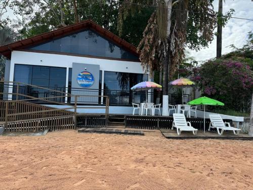 a building with chairs and umbrellas in front of it at Casa das Seringueiras in Alter do Chao