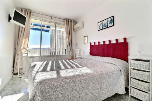 - une chambre avec un lit rouge et une fenêtre dans l'établissement T2 avec vue mer à 5 min de la plage, à Fréjus