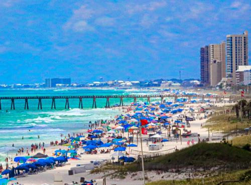 a beach with many people with umbrellas and the ocean at COUPLES GETAWAY, HONEYMOON SWEET, Perfectly Cozy Beach Front Condo with kitchen, pool, free parking,CHECK-IN AT DOOR in Panama City Beach