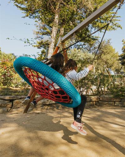 a young girl is riding on a swing at Camping Santa Elena in Lloret de Mar
