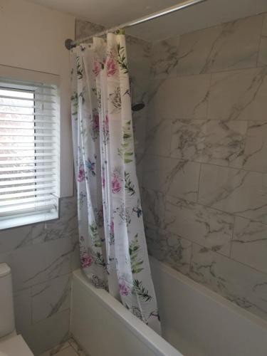 a bathroom with a shower curtain with flowers on it at Garden view Cosy Single Room in Derby
