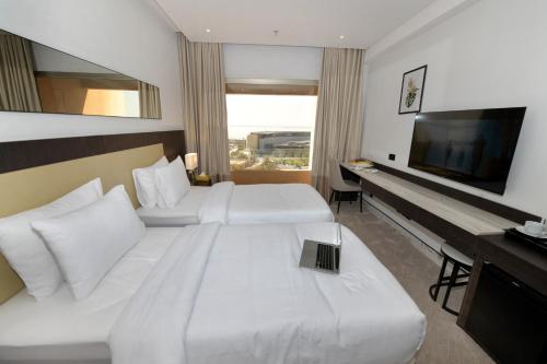 a hotel room with two beds and a flat screen tv at Carlton Tower Hotel Kuwait in Kuwait