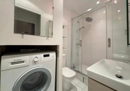 une salle de bain blanche avec une machine à laver et un lavabo dans l'établissement Immersion parisienne, Appartement au centre Paris, à Paris