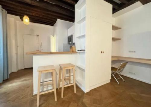 - une cuisine avec deux tabourets et un comptoir dans une pièce dans l'établissement Immersion parisienne, Appartement au centre Paris, à Paris