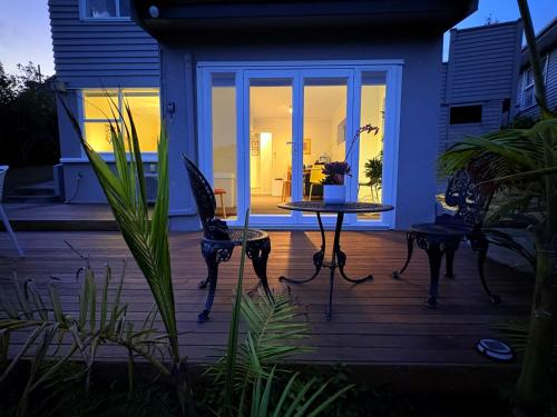 a patio with a table and chairs on a deck at Spacious & Secluded Bush-View Suite in Kohimarama in Auckland