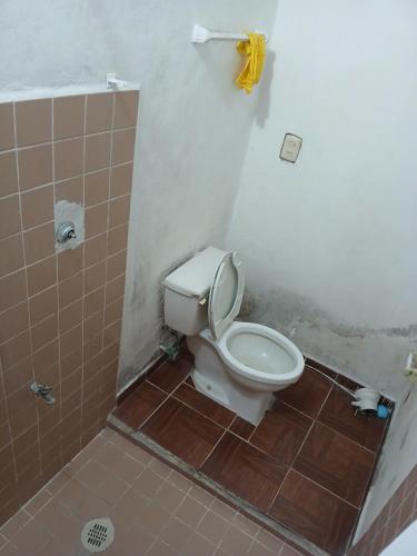 a bathroom with a toilet and a tiled floor at Rhinos House in Cozumel
