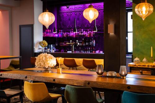 une salle à manger avec une table, des chaises et un éclairage violet dans l'établissement Hôtel-SPA Le Moulin De La Wantzenau - Strasbourg Nord, à La Wantzenau
