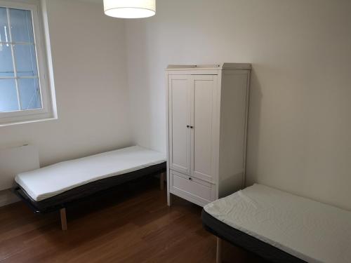 Cette chambre comprend 2 lits et une armoire blanche. dans l'établissement Le Cosy de Paray 4 couchages, à Paray-le-Monial