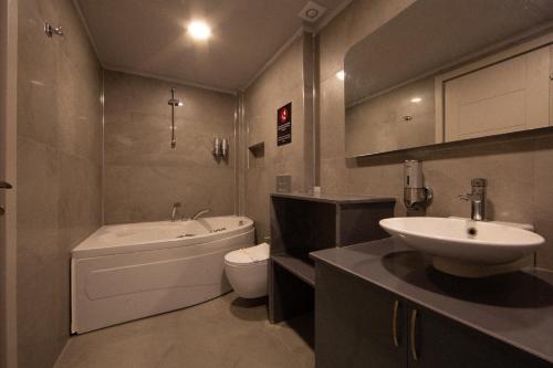 a bathroom with a sink and a tub and a toilet at Mesken Inn Göcek Hotel in Göcek