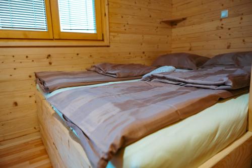 two beds in a log cabin with a window at Glamping Gril in Ljubno
