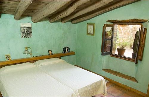 a bedroom with a white bed and a window at Cortijo Rural Finca HUERTA SANTA MARÍA in Galaroza
