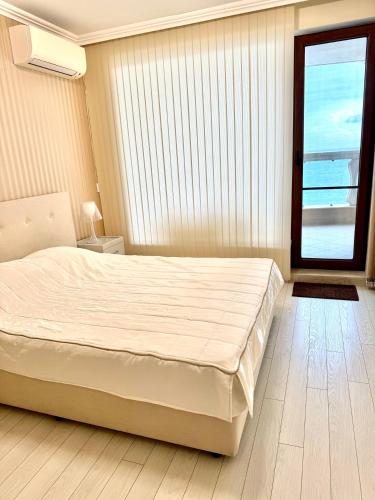a bedroom with a large white bed and a window at La Mer Welcome in Golden Sands
