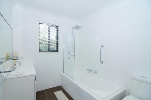 a white bathroom with a shower and a sink at Sandy Feet Getaway in Sanctuary Point