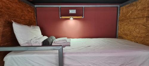 a bedroom with a white bed with a red wall at "The Sisters' Hostel" the women only hostel in Adeje