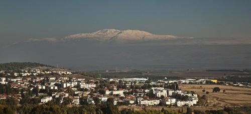 a city with a snow covered mountain in the background at Boutique Hotel Tamarin in Rosh Pinna