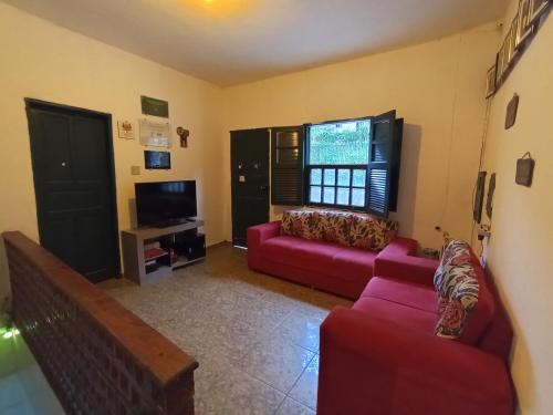 a living room with two red couches and a tv at República Engenho Quarto Casal in Ouro Preto