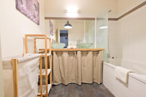 La salle de bains est pourvue d'un comptoir avec deux lavabos et d'une baignoire. dans l'établissement le cocon de Taillefer, à Périgueux