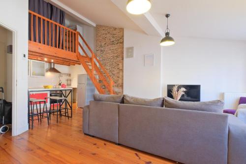 Il comprend un salon avec un canapé gris et une cuisine. dans l'établissement le cocon de Taillefer, à Périgueux