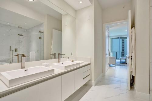 un bagno bianco con due lavandini e uno specchio di Luxury Ocean View 2BR a Riviera Beach