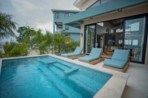 a swimming pool with two chairs and a house at Prana Maya Island Resort in Placencia Village