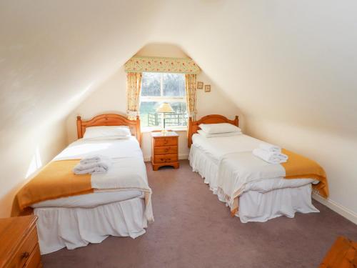 twee bedden op een zolderkamer met een raam bij Tile Rouge in Wooler