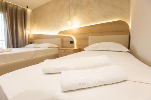 two beds in a hotel room with white sheets at Klebrido Hotel and Restaurant in Durrës