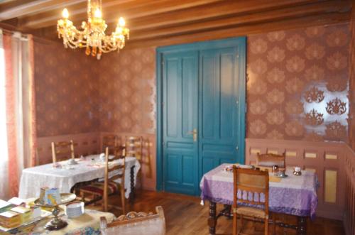 une salle à manger avec deux tables et une porte bleue dans l'établissement Lit en Loire, à Saint-Cyr-sur-Loire