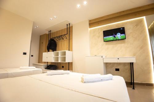 a bedroom with two beds and a tv on the wall at Klebrido Hotel and Restaurant in Durrës