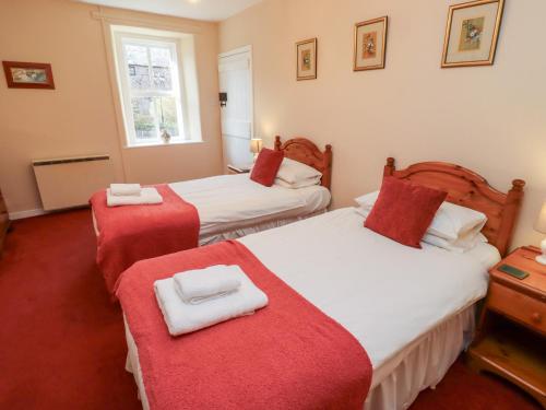 a bedroom with two beds with red and white sheets at Manor Cottage in Wooler