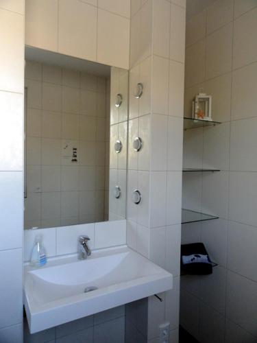 a white bathroom with a sink and a mirror at Haus Lütti in Glowe