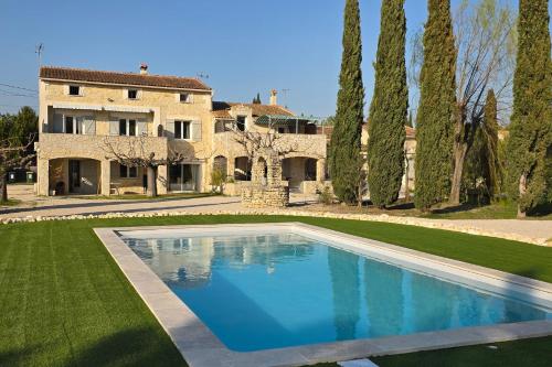 une grande piscine devant une maison dans l'établissement Locations des Alpilles, à Saint-Rémy-de-Provence