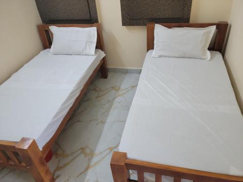 two beds in a room with white sheets at Medhaa Homes Madurai in Madurai