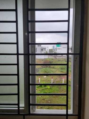 a window with a view of a field through it at Medhaa Homes Madurai in Madurai