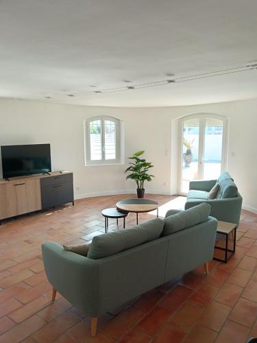 a living room with two couches and a tv at Villa Les Grenadines RDC in Mèze