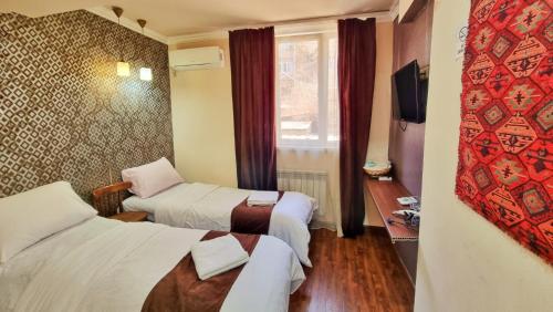 a hotel room with two beds and a window at Apple Hotel in Yerevan