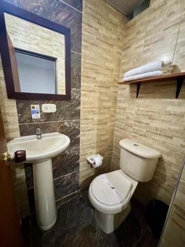a bathroom with a toilet and a sink at Hotel Tucan Pereira in Pereira