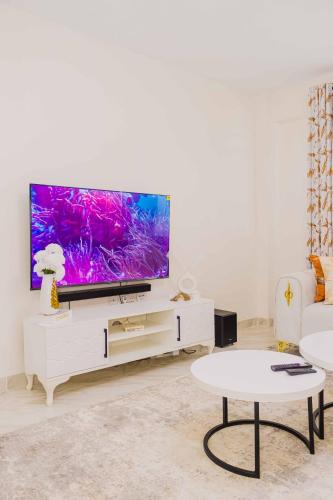 a living room with a flat screen tv on a white cabinet at Urban suites 2 bedroom Master ensuite holiday rental nanyuki in Nanyuki