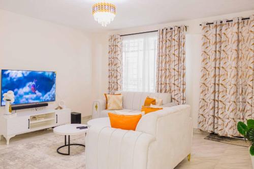 a living room with a white couch and a tv at Urban suites 2 bedroom Master ensuite holiday rental nanyuki in Nanyuki